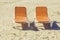 Two empty chaise lounges on the sand