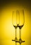 Two empty champagne glass on yellow background. Luxury drink glasses in yellow lights