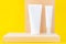 Two empty cosmetic tubes stand on a wooden board on a yellow background. Copy space for text. Minimalism concept, mock branding