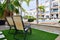 Two empty lounge chairs on artificial lawn grass inside of personal area backyard residential summer villa