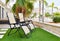 Two empty lounge chairs on artificial lawn grass inside of personal area backyard residential summer villa