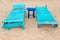 Two empty turquoise sunbeds at beach.