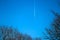 Two engine long-haul plane in the briight blue sky with contrail