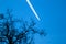 Two engine long-haul plane in the briight blue sky with contrail