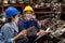 Two engineer or manager worker wearing safety helmet squat in the automotive part warehouse. Man looking at woman and smile.