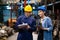 Two engineer wearing safety helmet standing in the automotive part warehouse. Man inspector the quality of good and write at paper