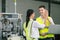 Two engineers clap together in an industrial warehouse. Large machinery