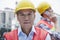 Two engineers in protective workwear working, looking at camera, outside of a factory