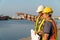 Two engineers stood wearing a safety helmet. Standing at the pier And holding the blueprint And consult the plan In the