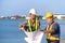 Two engineers stood wearing a safety helmet. Standing at the pier And holding the blueprint And consult the plan In the constructi