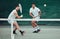 Two ethnic tennis players holding rackets and playing game on a court. Serious, focused team of athletes together during