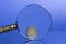 Two Euro coin on blue background through magnifying glass with nice reflection