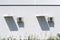 Two exteriors air conditioning units and their long shadows on a home white wall, under a hot summer sunny day