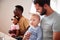 Two Families With Babies Meeting And Talking Around Table On Play Date