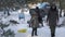 Two families grill kebabs in winter in a snowy pine forest.