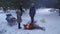 Two families grill kebabs in winter in a snowy pine forest.