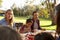 Two families having a picnic in a park, over shoulder view