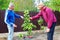 Two farmers discuss taking care of young pear tree in outdoor garden