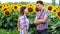 Two farmers shake a deal, man and woman in the agrarian sphere, talking in a field of sunflowers