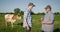 Two farmers shake hands, stand in a pasture where cows graze