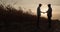 Two farmers shake hands, stand on the road between fields of corn at sunset