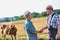 Two farmers shaking hands against brown cow in field