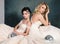 Two fashion gentle brides in wedding dresses pose in the studio