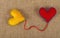 Two felt craft hearts, yellow and red on canvas