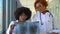 Two female african-american doctors examines x-ray of lungs, holding it in hands indoors. Two specialists holds