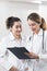 Two female assistants dressed in white coats talking to each other in the dentistry center