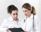 Two female assistants dressed in white coats talking to each other in the dentistry center