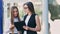 Two female businesswoman having informal team meeting standing outdoor near office