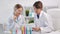 Two female chemist wearing uniform and protective glasses looking on paper document in lab