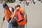 Two female cleaners in orange vests clean outside with tools, outdoor, summer