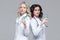 Two female doctors standing back-to-back hold ready-to-inject syringes