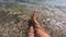 Two female feet are in clean transparent water on sandy beach on seashore