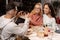 Two female friends asking man to take a picture of them in eating house.