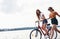 Two female friends on the bike have fun at beach near the lake