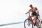 Two female friends on the bike have fun at beach near the lake