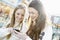 Two Female Friends Shopping In Mall Looking At Mobile Phone