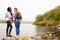 Two female friends standing by the edge of a lake laughing