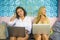 Two female friends working together outdoors at cool cafe with laptop computer , one girl caucasian , the other woman afro mixed