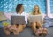 Two female friends working together outdoors at cool cafe with laptop computer , one girl caucasian , the other woman afro mixed