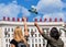 Two female with hands raised up with a white rose and a V sign on the background building with inscription FEAT of the PEOPLE