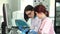 Two female lab workers operating analysing machines using computer