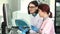 Two female lab workers operating analysing machines using computer