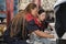 Two female mechanic workers are changing car wheel tires at a service garage.