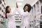 Two female multiethnical pharmacists in modern pharmacy. African and Caucasian women giving five each other, while