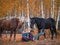 Two female riders sit on the grass next to the horses