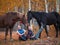 Two female riders sit on the grass next to the horses